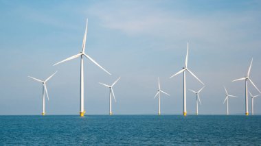 Rüzgâr değirmeni türbinleri ile rüzgar değirmeni parkı mavi gökyüzü yeşil enerji kavramına sahip elektrik üretiyor