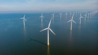 Rüzgâr değirmeni türbinleri ile rüzgar değirmeni parkı mavi gökyüzü yeşil enerji kavramına sahip elektrik üretiyor. Flevoland Hollanda