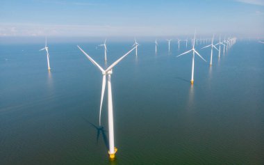 Mavi gökyüzü yeşil enerji kavramına sahip elektrik üreten yel değirmeni türbinleri