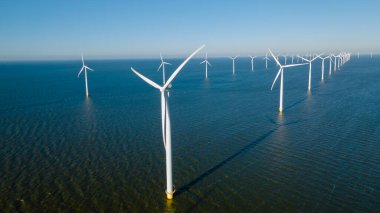 Rüzgâr değirmeni türbinleri olan, mavi gökyüzü yeşil enerji kavramına sahip elektrik üreten yel değirmeni parkı.