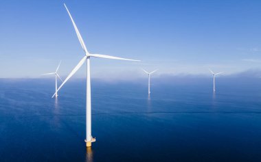 Yel değirmeni türbinleri ve bulutlu gökyüzü mavi gökyüzü yeşil enerji konseptiyle elektrik üreten yel değirmeni parkındaki hava manzarası.