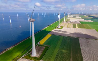 Yel değirmeni türbinleri ve bulutlu gökyüzü mavi gökyüzü yeşil enerji konseptiyle elektrik üreten yel değirmeni parkındaki hava manzarası.