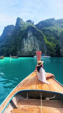 Pileh Lagoon Koh Phi Tayland 'da uzun kuyruklu bir teknenin önünde şapkalı genç Asyalı kadınlar..