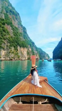 Pileh Lagoon Koh Phi Tayland 'da uzun kuyruklu bir teknenin önünde şapkalı genç bir Asyalı kadın..