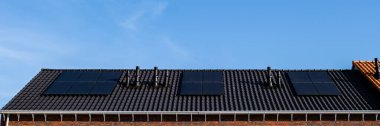Hollanda 'da güneşli bir gökyüzüne karşı çatıya bağlı güneş panelleri olan yeni evler inşa edildi.