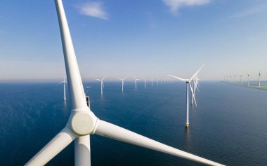 Yel değirmeni türbinleri ve bulutlu gökyüzü mavi gökyüzü yeşil enerji konseptiyle elektrik üreten yel değirmeni parkındaki hava manzarası.