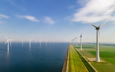 Yel değirmeni türbinleri ve bulutlu gökyüzü mavi gökyüzü yeşil enerji konseptiyle elektrik üreten yel değirmeni parkındaki hava manzarası.