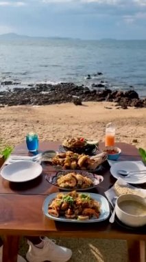 Gün batımında Pattaya Tayland sahilinde Tayland yemeği ve bbq balığı ile yemek masası.