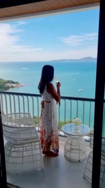 Asyalı kadınlar balkonda kokteyl içiyorlardı. Pattaya Tayland 'da bir otelin okyanusuna bakıyorlardı.. 
