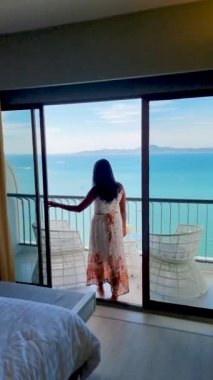 Asyalı kadınlar otelin balkonunda kokteyl içiyorlardı. Pattaya Tayland 'daki tropikal okyanusa bakıyorlardı.. 