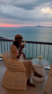 Asyalı kadınlar Susnet sırasında bir otelin balkonunda kokteyl içiyorlar.