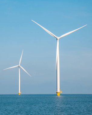 Mavi gökyüzü yeşil enerji kavramına sahip elektrik üreten yel değirmeni türbinleri