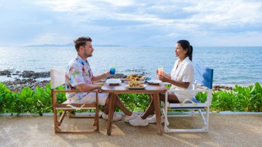 Bir çift, Pattaya Tayland Okyanusu 'na bakan bir restoranda öğle yemeği yiyor. Kadın ve erkek, Pattaya' da okyanus kenarında bir restoranda yemek yiyor.. 