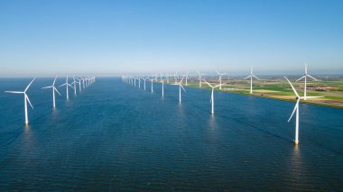 Hollanda 'da mavi gökyüzü yeşil enerji kavramına sahip rüzgar değirmeni türbinleri ile elektrik üreten yel değirmeni parkı