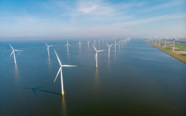 Denizdeki yel değirmeni türbinleri mavi gökyüzü yeşil enerji kavramına sahip elektrik üretiyor. Yel değirmeni parkında İHA görüntüsü