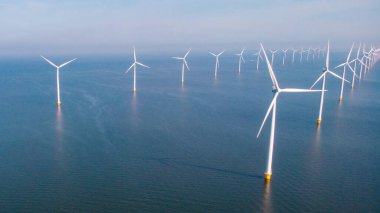 Denizdeki yel değirmeni türbinleri mavi gökyüzü yeşil enerji kavramına sahip elektrik üretiyor. Yel değirmeni parkında İHA görüntüsü