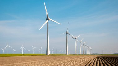 Rüzgâr değirmeni türbinleri mavi gökyüzü yeşil enerji konseptiyle elektrik üretiyor.