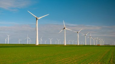 Yel değirmeni türbinleri, Hollanda Flevoland Ijsselmeer 'deki rüzgar değirmeni parkında mavi gökyüzü yeşil enerji kavramına sahip elektrik üretir. 