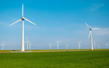 Mavi gökyüzü yeşil enerji konseptiyle elektrik üreten büyük türbinleri olan yel değirmeni parkı.