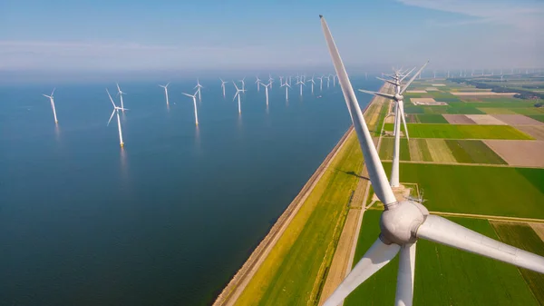 Windmill turbines at sea generating electric with a blue sky green energy concept. Drone aerial view at windmill park