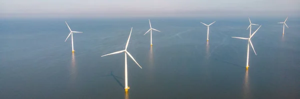 Drone aerial view at Windmill in the ocean turbines generating electricity with a blue sky green energy concept
