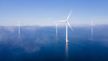 Rüzgâr değirmeni parkındaki hava manzarası kış boyunca türbinlerle mavi gökyüzü yeşil enerji kavramına sahip elektrik üretiyor.