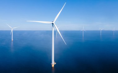 Rüzgâr değirmeni parkındaki hava manzarası kış boyunca türbinlerle mavi gökyüzü yeşil enerji kavramına sahip elektrik üretiyor.