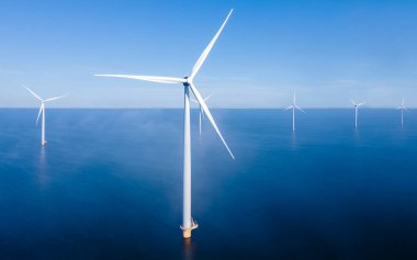 Aerial view at Windmill park with windmills turbines during winter generating electricity with a blue sky green energy concept clipart