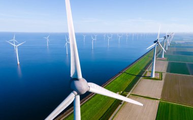 Rüzgâr değirmeni parkındaki hava manzarası kış boyunca yel değirmenleri türbinleriyle mavi gökyüzü yeşil enerji konseptiyle elektrik üretiyor. Bulutlu rüzgar değirmeni