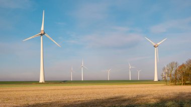 Rüzgâr değirmeni türbinleri ile kış boyunca mavi gökyüzü yeşil enerji kavramına sahip elektrik üreten yel değirmeni parkı