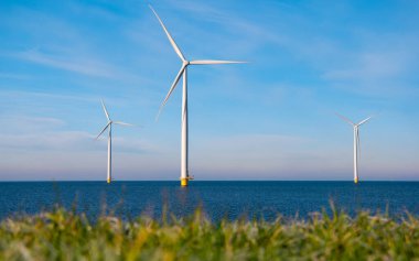 Aerial view at Windmill park with wind mill turbines during winter generating electricity with a blue sky green energy concept clipart