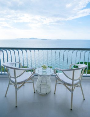 Bir otelin balkonunda mavi okyanus manzaralı sandalyeler.