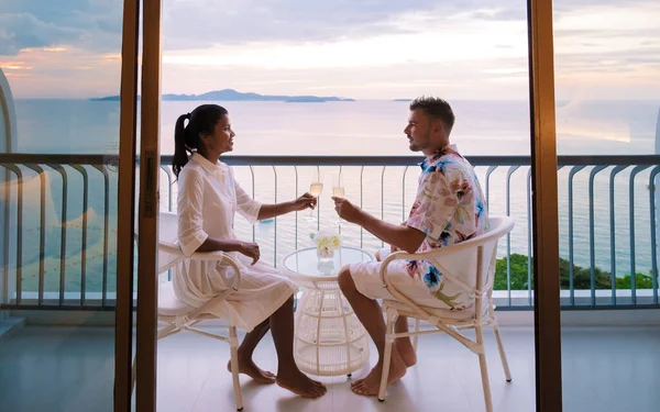 两名男子和妇女日落时在泰国帕塔亚一家酒店的阳台上喝鸡尾酒 — 图库照片