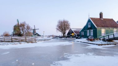 Kış boyunca Zaanse Schans yel değirmeni köyü kışın gün doğumunda Hollanda 'nın Hollanda köyünde kar manzarası ile