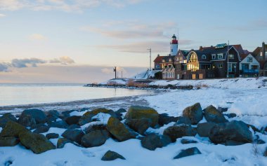 Güneşli bir günde Hollanda 'da kar manzaralı Urk deniz feneri