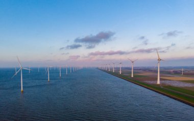 Gün batımında Hollanda 'da yel değirmeni türbinleri olan yel değirmeni parkı
