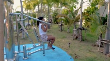 Pattaya Tayland 'da bir halk parkında Asyalı kadınlar spor yapıyor. Taylandlı olgun bir kadın şehirde palmiye ağaçlarıyla parkta egzersiz yapıyor.
