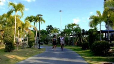 Pattaya Tayland 'da halka açık bir parkta koşan iki Asyalı kadın egzersizi. Kadın arkadaşlar koşuyor. Taylandlı olgun bir kadın şehirde palmiye ağaçlarıyla parkta egzersiz yapıyor.