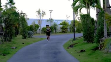 Pattaya Tayland 'da palmiye ağaçları olan yeşil bir parkta koşan Asyalı kadınlar. 