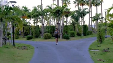Pattaya Tayland 'da palmiye ağaçları olan yeşil bir parkta koşan Asyalı kadınlar. 