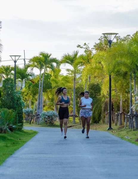 两名亚洲妇女在泰国帕塔亚的一个公园跑步 女性朋友慢跑 泰国成年女子在一个有棕榈树的公园里锻炼 — 图库照片