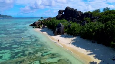 Anse Source DArgent sahilinde yürüyen iki kadın ve erkek Seyşeller 'in en güzel plajı. La Digue Adası, Seyşeller. 