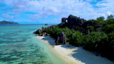 Anse Source DArgent sahilinde yürüyen iki kadın ve erkek Seyşeller 'deki en güzel plajdır. La Digue Adası, Seyşeller güneşli bir günde