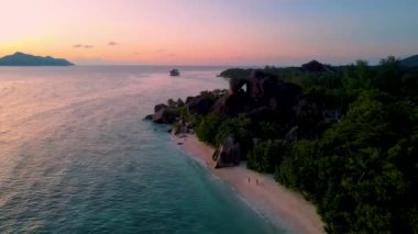 Anse Source DArgent 'ın günbatımında sahilde yürüyen iki erkek ve kadın Seyşeller' deki en güzel plajdır. La Digue Adası, Seyşeller. 