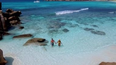 Birkaç erkek ve kadın Anse Cocos plajında, Seyşeller La Digue Adası 'nda, Petite Anse Sahili' nde beyaz kum ve turkuaz renkli okyanuslarla dolu güzel bir plajda yüzüyor.. 