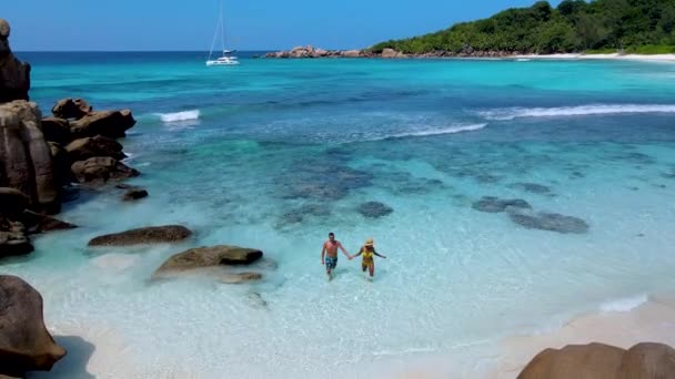 男女のカップルがAnse Cocosビーチで泳ぐセイシェル ディゲ島 小柄なAnseビーチセーシェルの白い砂とターコイズブルーの海を持つ美しいビーチ — ストック動画