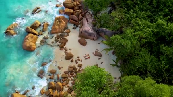 塞舌尔普拉斯林岛安塞拉齐奥海滩上的一对情侣 俯瞰着躺在海滩上岩石上的男男女女 — 图库视频影像