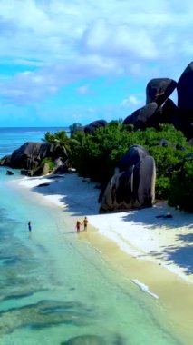 Birkaç erkek ve kadın Anse Source DArgent La Digue Adası, Seyşeller sahilinde yürüyorlar.. 