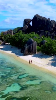 Birkaç erkek ve kadın sabahın erken saatlerinde Anse Source DArgent plajında yürüyorlar. Seyşeller 'de güzel bir plaj. La Digue Adası, Seyşeller. 