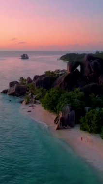 Günbatımında Anse Source DArgent plajında bir çift kadın ve erkek, Seyşeller 'de güzel bir plaj. La Digue Adası, Seyşeller. 